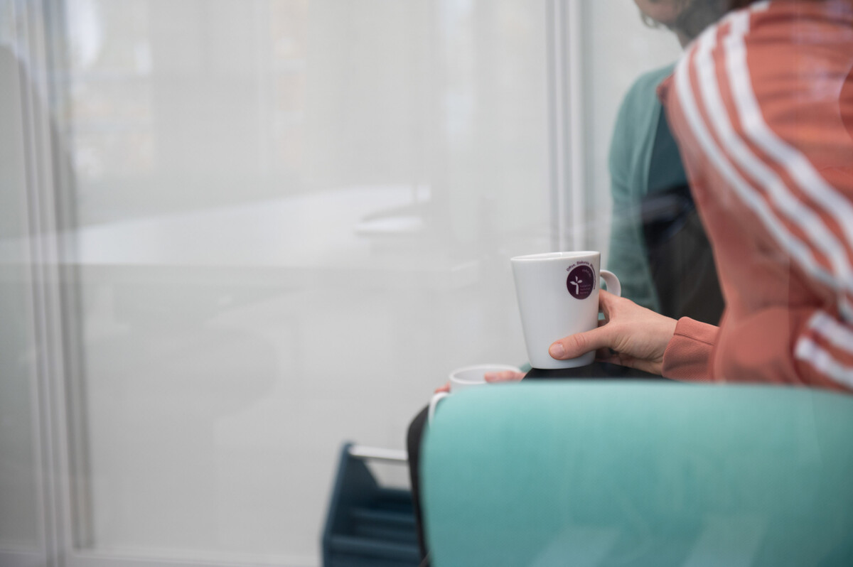 Eine Person hält eine Kaffeetasse mit EVHN-Logo in der Hand