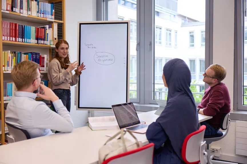 Eine Gruppe Studierender macht eine Gruppenarbeit in einer Bibliothek