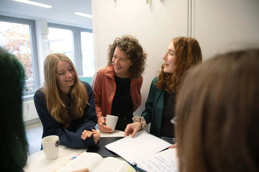 Einige Studiernde stehen in einer Gruppe und unterhalten sich fröhlich