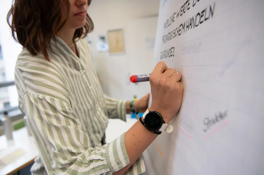 Eine Studierende schreibt in einem Seminar auf ein Flipchart