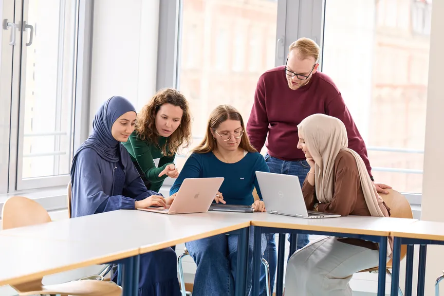 Eine Gruppe Studierender arbeitet an Laptops